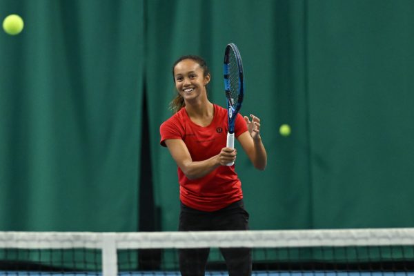 NCAA player Bianca Jolie Fernandez smiles as she follows through on a forehand.