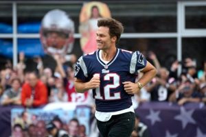 Former NFL QB Tom Brady runs onto the field at Gillette Stadium.