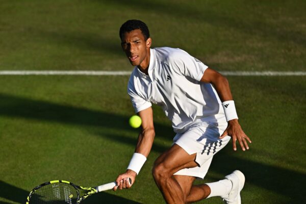 Felix Auger-Aliassime hits a low forehand during his match with Thanasi Kokkinakis at Wimbledon.