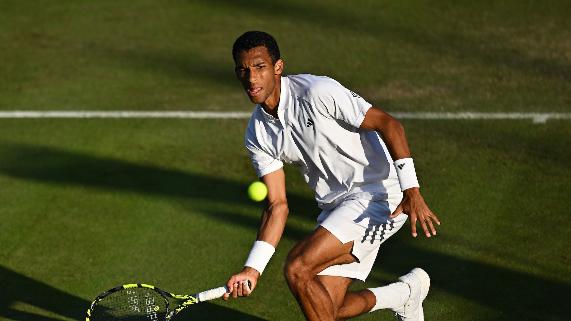 Felix Auger-Aliassime hits a low forehand during his match with Thanasi Kokkinakis at Wimbledon.