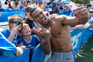 Detroit Lions wide receiver Amon-Ra St. Brown uses someoneÕs iPhone to do a selfie with kids after practice at the Detroit Lions training facility in Allen Park on Wednesday, August 14, 2024.
