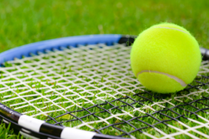 Tennis ball and racket on grass