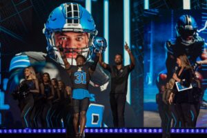 Kerby Joseph (31) and Calvin Johnson stand on stage during the Detroit Lions' new uniform reveal event inside Ford Field in Detroit on Thursday, April 18, 2024.